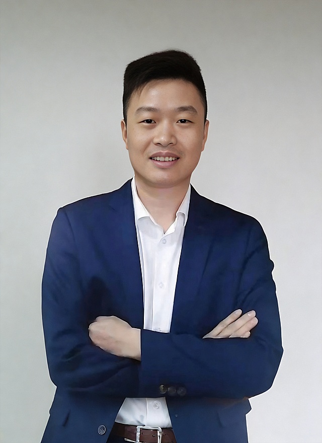 为这张形象照更换背景，将原白色背景改为均匀柔和的浅灰色纯色背景，保留人物、服装和姿势不变，保持专业商务质感，不改变人物细节和整体构图