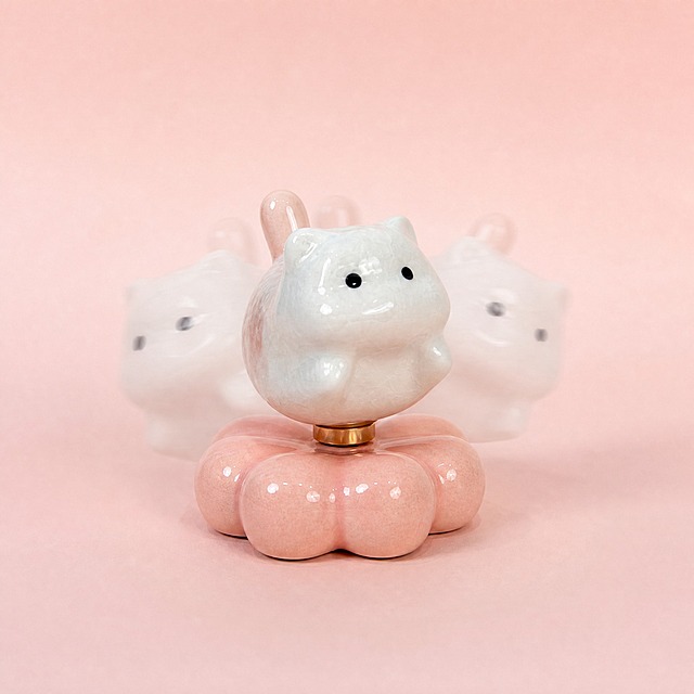 Amazon e-commerce main image 2, 1:1 square, cute decompression rotating ceramic cat toy gift, white ceramic cat sitting on pink flower base, showing rotating function with subtle motion blur effect, side angle view, soft gradient light pink background, premium ceramic texture, shiny glaze, professional product photography, no text, commercial quality