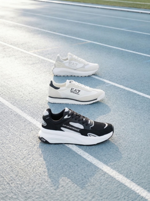 将三只运动鞋按照参考图的角度依次排列放置在浅灰蓝运动跑道背景上，从上到下依次是全灰白色运动鞋、白黑配色运动鞋、黑白配色运动鞋，高度还原参考图的摆放角度和透视效果，光线自然融合，整体画面协调预览效果