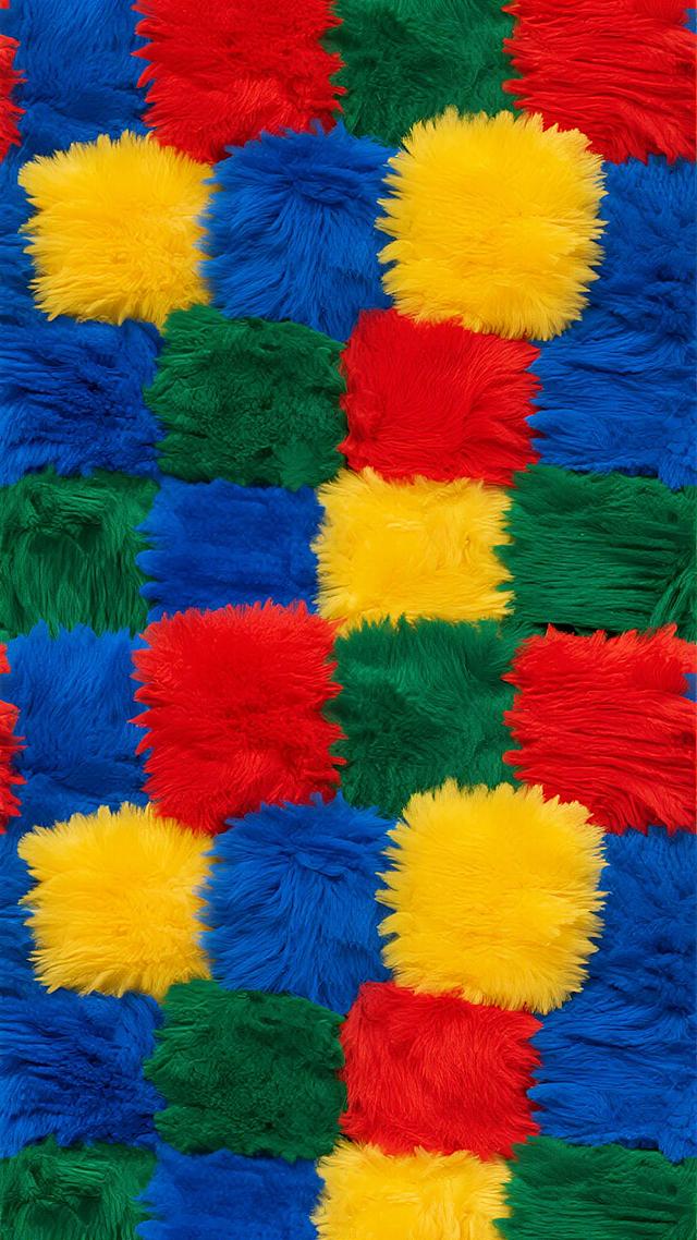 一张由柔软蓬松的毛绒面料构成的无缝图案，采用撞色系设计，以明亮饱和的宝蓝色、鲜黄色、正红色和翠绿色的毛绒块不规则交错排列，每个毛绒块都具有细腻的绒毛纹理和自然的光影过渡，整体保持了原有的毛绒质感和紧密排列的构图风格，色彩对比强烈且充满活力，营造出欢快跳跃的视觉效果。