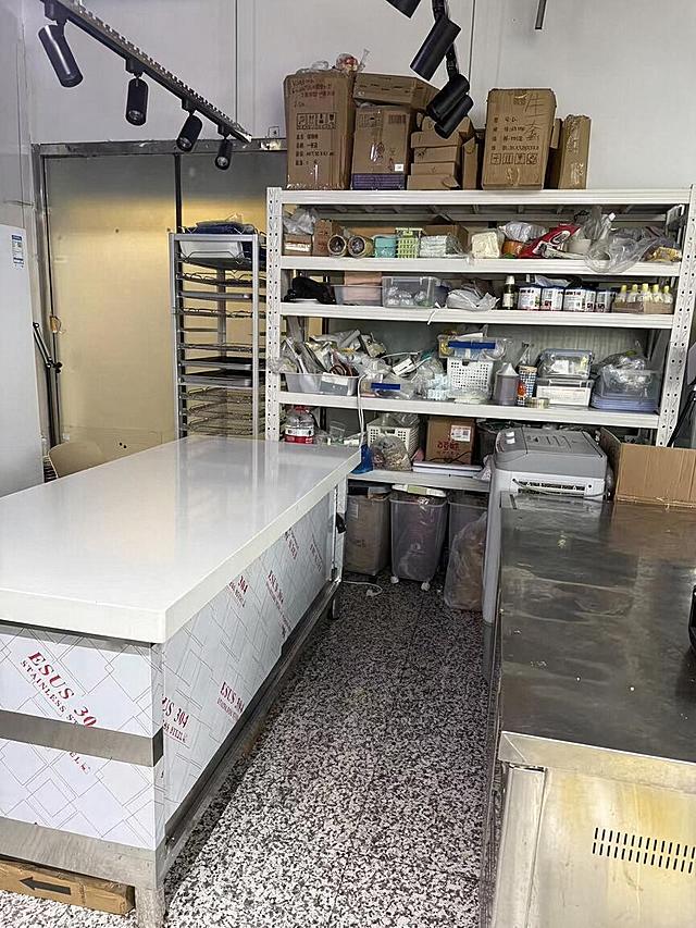 去除后方白色货架右上角被透明塑料袋包裹的风扇设备，去除后用周围真实的白色墙面和货架顶部结构自然填充，光影和材质与原图完全一致，过渡自然无痕。严格保持图片中其他所有主体、物品、细节、结构、颜色、光线、透视角度完全不变，不得添加或修改任何其他元素。最后整体提升图片清晰度，画质自然真实，保持原照片的真实感。