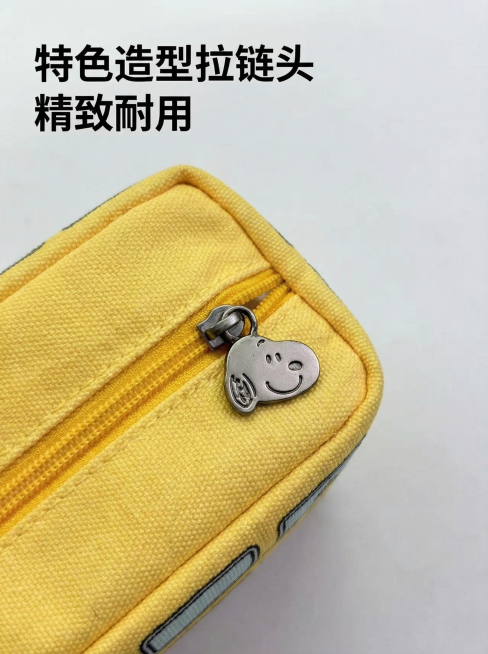 [主图 3] 细节展示，放大展示黄色史努比巴士笔袋的史努比造型拉链头细节，背景为浅色纯色，突出金属拉链头的独特设计，展示精致做工，保持和参考图拉链头细节、颜色完全一致，画面清晰锐利，左上角悬浮文字“特预览效果