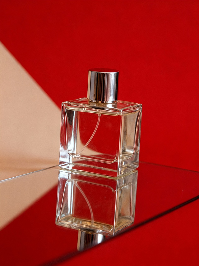 极简摄影风格，产品（占画面比约40%）置于镜面上，对角线构图，无多余装饰，红色背景，高级时尚氛围，极简布光保障融图效果。