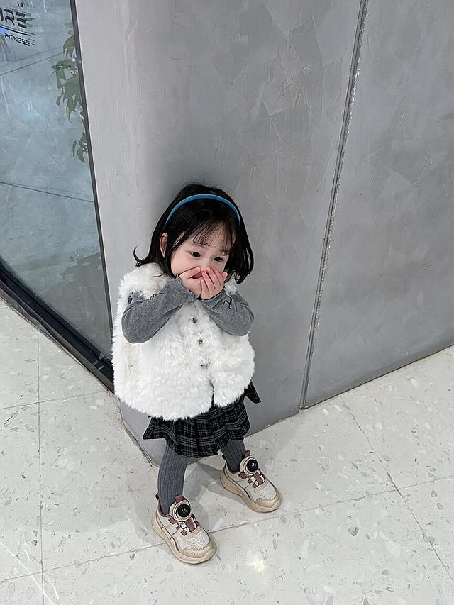 将图中人物脚上的棕色短靴替换为第一张图中的米白紫配色旋钮扣儿童运动鞋，保持人物姿势、服装、背景和整体画面风格不变，鞋子角度和透视与脚部姿态自然匹配，光影真实自然