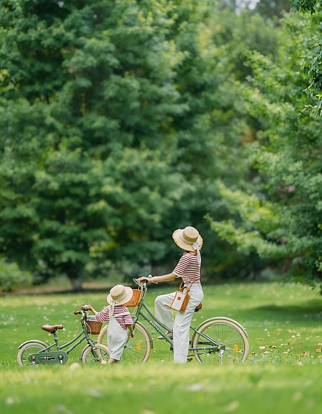 生成类似风格的亲子骑行竖图，背景虚化，画面中不要文字，呈现温馨治愈的户外亲子骑行场景，人物穿着简约清新的服饰，搭配复古风格自行车