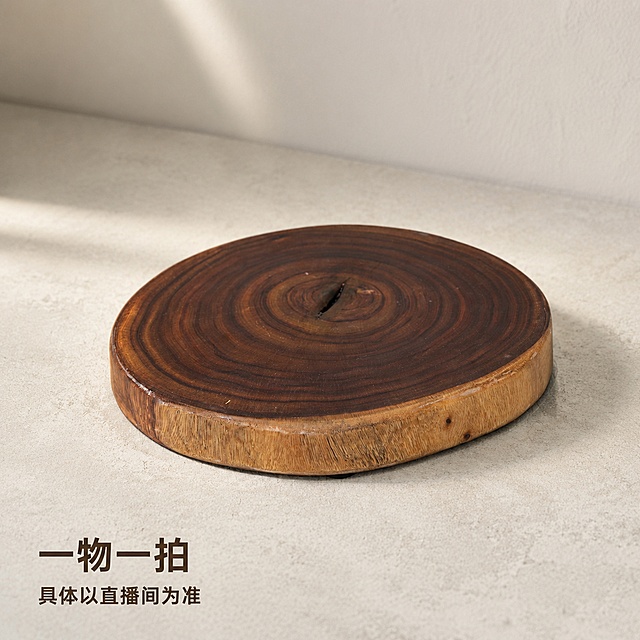 [主图-1] 自然原木圆形实木底座摆件，侘寂风家居展示。氛围风格：温馨侘寂风，简约自然高级感。画质：商业摄影质感、光线柔和通透、产品清晰真实、画面干净高级。元素：原木圆形底座放置在侘寂风素色水泥台面上，背景为简约米白墙面，产品为唯一视觉中心，主体占比约70%。保持原木圆形底座外观，物理结构、年轮纹理、材质质感、颜色与输入产品图绝对一致，杜绝任何变形和色差，精细化处理。商品主体占比严格控制在60%-80%之间。光影：自然光从左侧斜射，形成柔和阴影，突显木材纹理层次，整体光线均匀通透。配色：主色调原木棕，背景素白浅灰，整体低饱和自然配色。视角构图：45度斜侧平视，景深适中，产品完整不裁切。文字版式：左下角负空间放置两行文字，大字"一物一拍"，小字"具体以直播间为准"，深棕色粗体无衬线字体，文字清晰不遮挡产品主体，保留安全边距。比例分辨率：1:1比例，4k分辨率；文字清晰锐利，画面超高清。负向提示词：变形，文字错乱，产品图模糊，背景杂乱，水印，电商平台Logo。