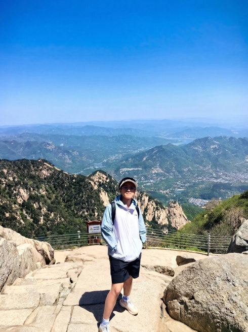 去除图片中除中心小孩以外的所有其他人，保留山峦景观和石阶路径，修复被人物遮挡的背景，保持整体自然真实预览效果