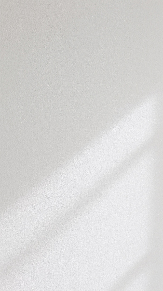 一面纯白色的墙面，表面具有细腻均匀的磨砂质感纹理，整体呈现出柔和的哑光光泽，光线均匀地漫反射在墙面上，营造出简洁、干净、素雅的氛围，墙面平整无任何装饰和瑕疵，展现出纯粹的材质本身的朴素美感。