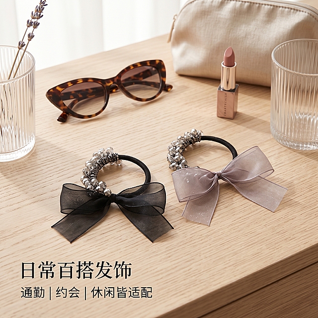 严格还原上传的两款发圈实物图，产品外观必须和参考图完全一致，不改动弧形切面水晶串珠结构、网纱蝴蝶结版型、黑色弹力发绳；完整保留两个配色【黑色网纱款、灰雾紫闪纱款】；保持真实材质质感：水晶珠高光通透、网纱轻薄微闪、皮筋哑光柔软；1:1 正方形竖图，ins 韩风生活场景摄影，柔和窗边自然光；场景布置：简约原木梳妆台，搭配墨镜、淡色系口红、玻璃杯作为时尚道具；两款发圈错落摆放在台面；画面左下角主标题【日常百搭发饰】，副标题【通勤｜约会｜休闲皆适配】；文字左下角排版，不抢占画面视觉重心；整体氛围感柔和治愈，生活化美学杂志版面。负面提示词：场景拥挤杂乱，道具过多；滤镜厚重失真；产品扭曲变形；模特头部 / 人脸出镜；文字密密麻麻堆砌；色彩冷暖失衡；多余包装袋、垃圾杂物
