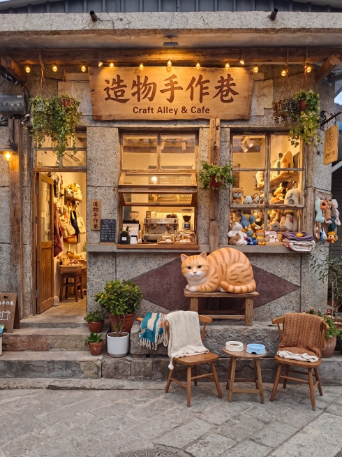 将这栋石头房子改造为"造物手作巷"咖啡厅，售卖宠物周边产品同时提供咖啡，保留上一次设计中的大橘猫雕塑造型，采用温馨治愈风格，生成改造后的店铺外观效果渲染图，门头招牌写上"造物手作巷"预览效果