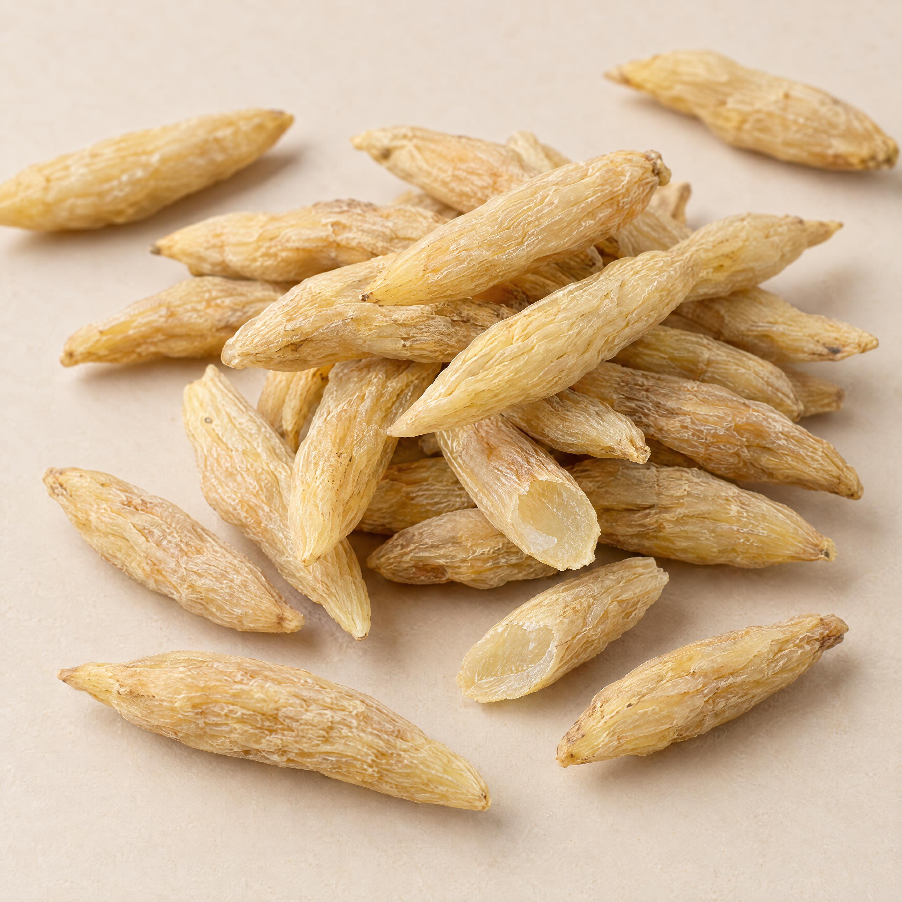 一张中药材麦冬的高清特写照片，麦冬呈纺锤形，两端略尖，表面黄白… - 图片创意预览