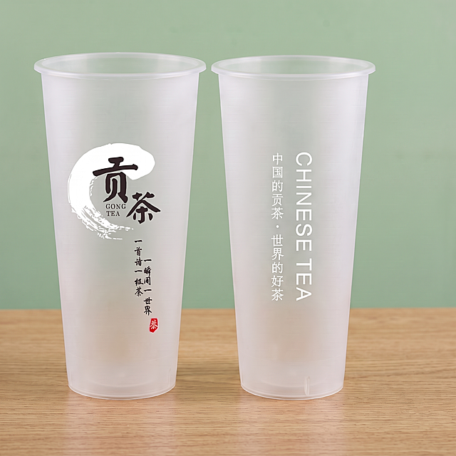 在图片的上下左右添加均匀留白，保持两个贡茶杯子的杯型、尺寸、颜色、磨砂质感、所有文字图案完全不变，保持木色桌面和绿色背景不变，仅增加留白，1:1比例，超高清商业摄影质感