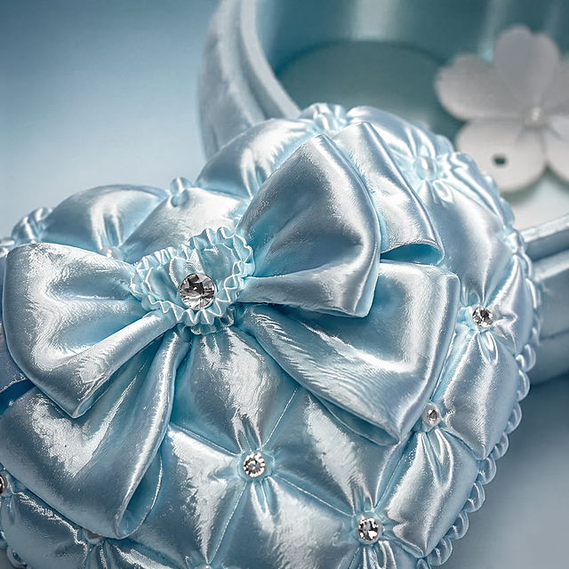 [Main Image 3] Macro detail close-up of the satin bow and diamond decoration on the jewelry box. Emphasize the delicate satin texture, the quilting stitching details, the sparkling clear diamond embellishment. Light blue low-saturation gradient background, side backlight to show the material's luster and texture. Keep product detail consistent with original image. 1:1 square, 4K commercial photography, high sharpness. negative prompt: deformation out of focus blurred.