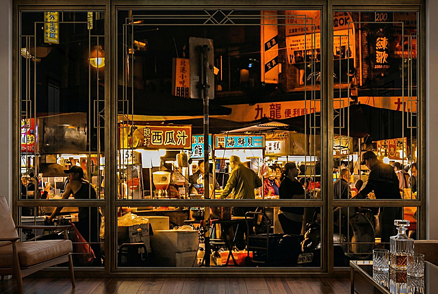 从精致高级的金属边框落地窗内视角，窗外是和参考图风格一致的热闹夜市街区，暖黄灯光，繁体招牌，人群穿梭，充满烟火气