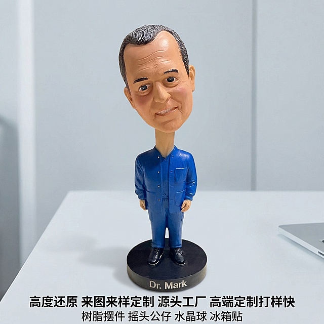 [垫图] https://gdesign-dam-hz.dancf.com/35909032190005285/54c09fd3a2034f7eaad716e3a1686445.jpg
[主图主题] 蓝色衣服名人公仔电商主图
[氛围/风格] 明亮清晰商务办公风格，超高清写实，质感细腻，背景简约办公风
[画面元素] 蓝色衣服名人公仔摆件放置在平整浅灰色办公桌面上，保留原图产品造型、颜色、比例和正面角度完全不变，背景替换为纯净简约的办公室浅灰色墙面背景，产品主体完整居中展示，占据画面约60%区域，柔和自然光突出树脂纹理和立体轮廓，背景干净无任何多余杂物
[配色色系] 主色：产品自身蓝色 棕色 黑色；辅助色：浅灰色办公桌面，浅灰色办公背景，色彩商务协调
[视角构图] 完全保留原图正面拍摄角度，景深适中，主体清晰突出，边缘完整不切割
[文字版式] 图片底部桌面区域居中放置文字，第一行黑色文字"高度还原 来图来样定制 源头工厂 高端定制打样快"，第二行黑色文字"树脂摆件 摇头公仔 水晶球 冰箱贴"，字体大小对比清晰，文字分行居中排列，完全不遮挡产品主体，四周保留充足安全边距，整体构图平衡舒适，符合国内电商主图规范。