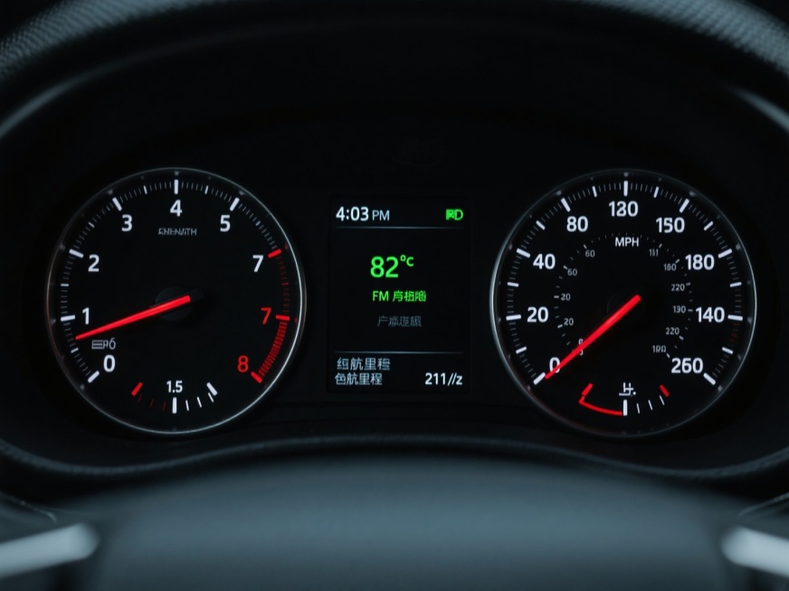 汽车仪表盘特写，黑色背景，左右两侧为圆形仪表，左侧转速表刻度0-7，指针指向1.5，右侧速度表刻度0-140 MPH，指针指向0，中间为黑色显示屏，显示时间4:03 PM、温度82°F、FM广播、续航里程211英里等信息，白色刻度与数字，红色指针尖端，绿色数字显示，仪表盘边缘有细密纹路，整体呈现写实风格，光线柔和，细节清晰，营造出科技感与精准感。预览效果
