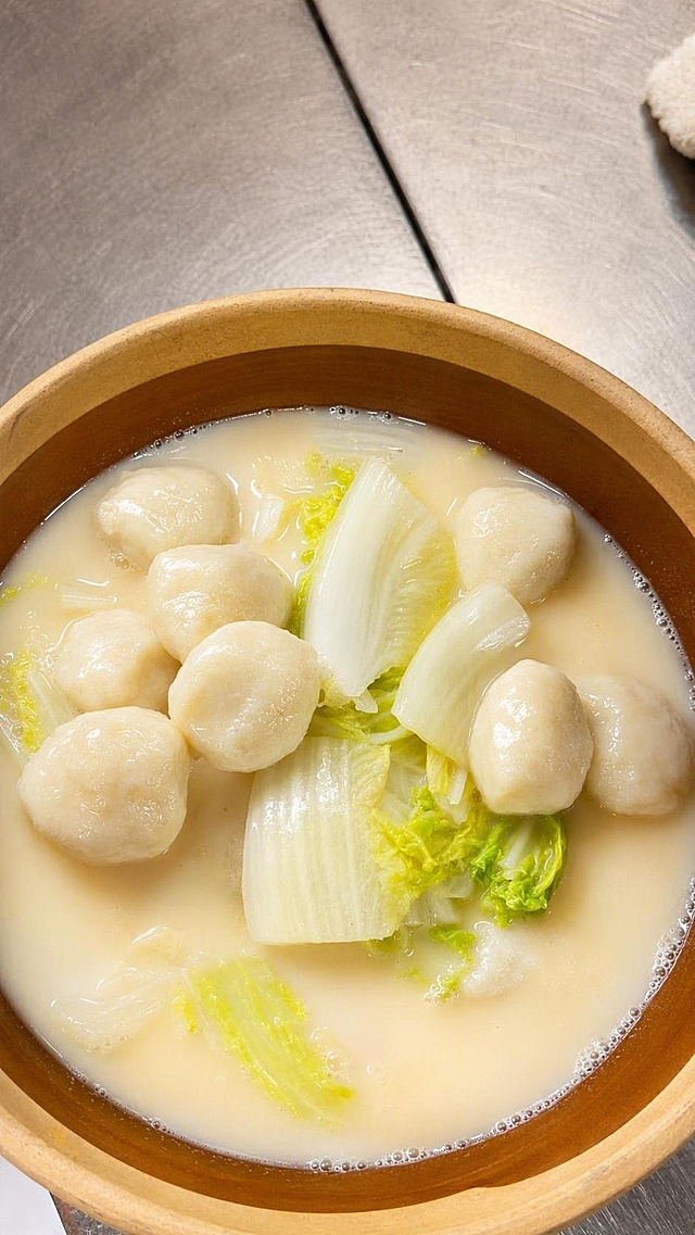 美食摄影风格，美化这道鱼丸白菜汤，让鱼丸饱满莹润有光泽，汤色奶白浓郁有质感，白菜鲜脆透亮，整体光线柔和明亮，色调温暖有食欲，画面清晰干净，高端餐厅美食大片效果，保持菜品和摆盘原样不变