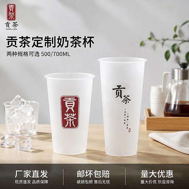 [主图-1] 贡茶一次性奶茶杯首图，产品场景陈列展示。
[氛围风格] 干净通透家居餐厨风，明亮自然光，清爽实用质感，真实商品展示。
[画质] 商业摄影质感、光线柔和通透、产品清晰真实、画面干净高级。
[元素] 保持产品外观（物理结构、磨砂材质、颜色、印刷内容）与输入产品图绝对一致，杜绝任何变形和色差，精细化处理。500ml和700ml两款杯子并排居中展示，放置在浅原木色奶茶店操作台上，背景为浅灰色干净墙面，搭配半杯冰块做道具点缀，商品主体占比严格控制在60%-80%之间，画面满屏无边框。左上角保留贡茶品牌标识，安全边距不遮挡主体。
[光影] 明亮侧窗自然光，整体高亮通透，磨砂杯体漫反射自然柔和，背景浅亮不抢主体，轮廓清晰，阴影过渡自然。
[配色] 主色调浅原木色+浅灰，辅助色杯子磨砂本白色，品牌标识黑红原色，整体干净舒适。
[视角构图] 平视45度斜拍，景深适中，产品主体完整清晰，不裁切。
[文字版式] 左上负空间左对齐，大字主文案“贡茶定制奶茶杯”黑色粗体无衬线，下方小字“两种规格可选 500/700ML”同色系缩小一半。底部通栏半透明渐变蒙层均分三列，左列大字“厂家直发”中字说明，中列“邮坏包赔”，右列“量大优惠”，均为白字深底对比强烈，排版清晰。
[比例分辨率] 1:1 比例，4k 分辨率，文字清晰可辨，超高清。
[负向提示词] 变形，文字错乱，产品图模糊，背景杂乱，水印，电商平台Logo，绝对化违禁词。
