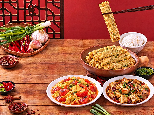 将图中所有卷煎替换为第七张参考图中的卷煎样式（表面有褶皱纹理、色泽金黄油亮、带少量绿色碎末的长卷状），筷子夹着的那根卷煎要做得更长一些，保持原图的构图、光线、背景、其他菜品和餐具完全不变，美食摄影风格，高清写实