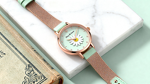 A close-up, high-end product photography of a luxury women's wristwatch for the brand "Daisy Buchanan". The watch has a small, elegant dial with a daisy flower motif as the second hand or inside the dial. The strap is rose gold metal mesh or pastel green leather. Placed on a vintage book or a piece of white marble. Soft natural lighting, pastel aesthetic, clean background. Extremely detailed, 8K, C4D render, minimalist, elegant