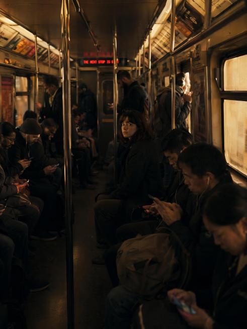 Subway car full of people all looking down at phones, warm window light, one person looking up at th预览效果