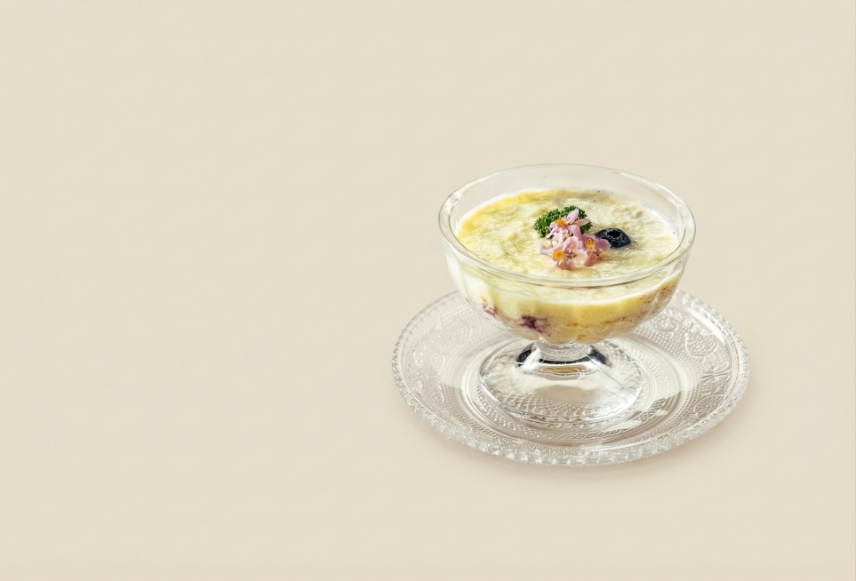 保留玻璃甜品杯和甜品的原有主体结构不变，仅将背景替换为纯净的燕麦色纯色背景，使用全屋漫射柔光，低对比度，阴影极淡且柔和，画面明亮干净通透，添加极淡的接触阴影，玻璃材质透出柔和的环境反光，消除抠图白边，预览效果