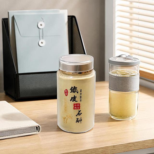 将图中的银色罐头产品替换为上传的亚克力罐铁皮石斛粉产品，完整保留亚克力罐产品本体上的所有文字信息、材质、颜色和轮廓结构，自然融入原场景的桌面、背景和光影，和原有场景光影保持一致，与场景共处同一物理空间，产品为第一视觉焦点，主光方向和亮度与原图一致，亚克力瓶的反光自然，严格锁定宽高比为1:1