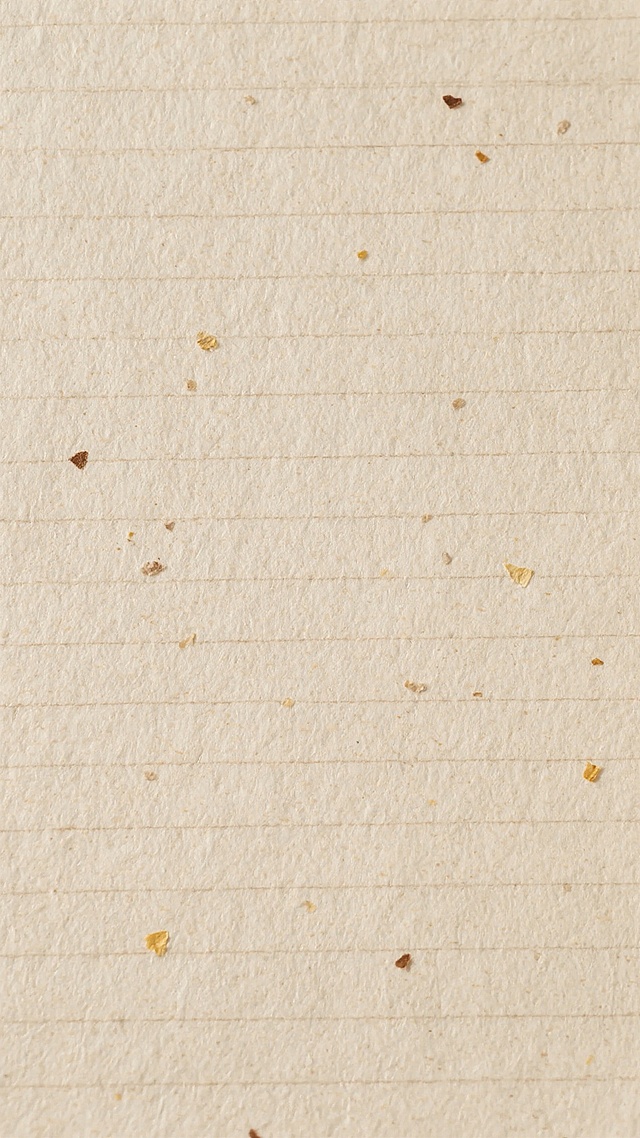一张米色质感的纸张纹理背景，纸张表面带有自然的纤维纹路和细微的横向纹理，散布着少量细小的棕色和黄色纸浆颗粒杂质，整体呈现出柔和、朴素且略带粗糙的手工纸张质感，光线均匀，无明显阴影，营造出一种复古、自然、原生态的氛围。