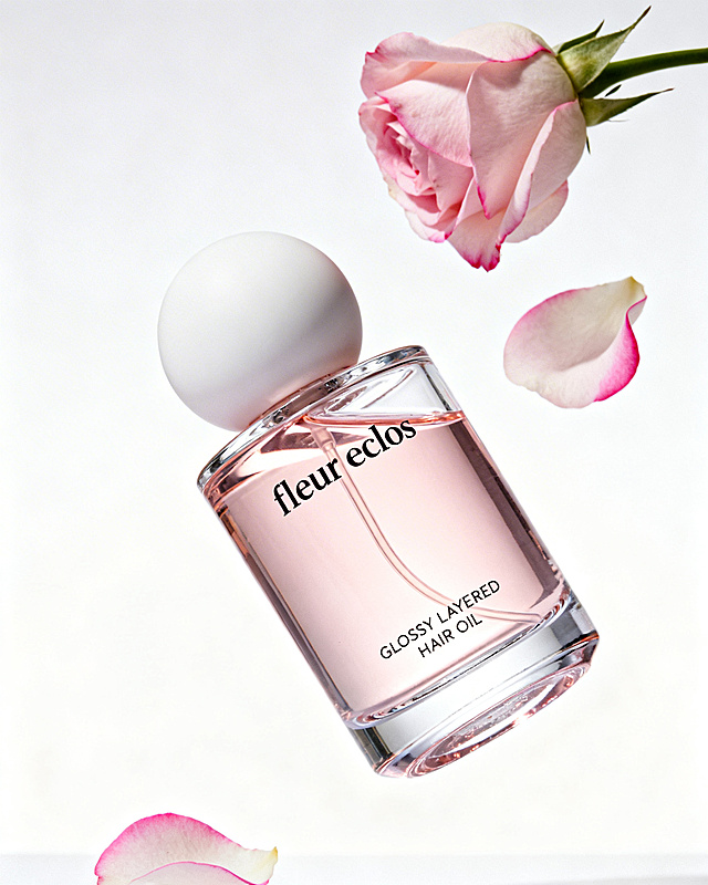 极简柔美感fleur eclos护发精油摄影提示词 主体为fleur eclos护发精油（粉调透明玻璃瓶身+哑光白球形瓶盖，含浅粉精油液，印“GLOSSY LAYERED HAIR OIL”等文字），搭配飘落的粉玫瑰花瓣元素，构图呈倾斜悬浮的空间层次，呈现柔美、灵动的调性；色彩以柔粉、透白、哑光白为主色调，色调清甜柔和，画面风格为高质感护发品商业静物摄影，细节清晰（如玻璃瓶身的通透光泽、玫瑰花瓣的