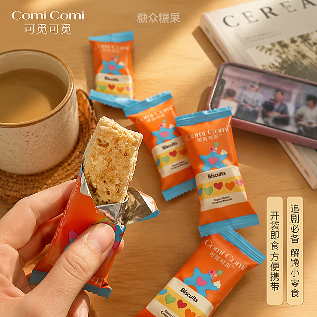 抖音电商1:1正方形主图，生活场景食用体验图。暖橙温馨风格。画面为Vlog第一人称视角抓拍，一只手（仅露出手部局部）正拿起拆开的蛋黄味花生酥准备送入口中，桌面上散落着多包Comi Comi可觅可觅花生酥独立小包装（橙蓝配色，星星爱心图案），还有一杯热茶或咖啡，旁边放着手机和杂志，营造休闲下午茶追剧场景。浅木色桌面，暖黄色柔和自然光，背景虚化有氛围感。画面顶部正中间放置水印「糖众糖果」，半透明浅灰色简洁字体。左上角放置品牌Logo「Comi Comi 可觅可觅」。右下角文案竖排或横排小标签：「追剧必备 解馋小零食」「开袋即食 方便携带」。食物实体诱人，酥松质感清晰。商业生活摄影质感，自然真实有代入感。1:1比例。负向：多余的手，多余的手指，畸形手，融合手指，手部扭曲，人物面部扭曲，变形，文字错乱，产品模糊，背景杂乱，电商平台Logo。