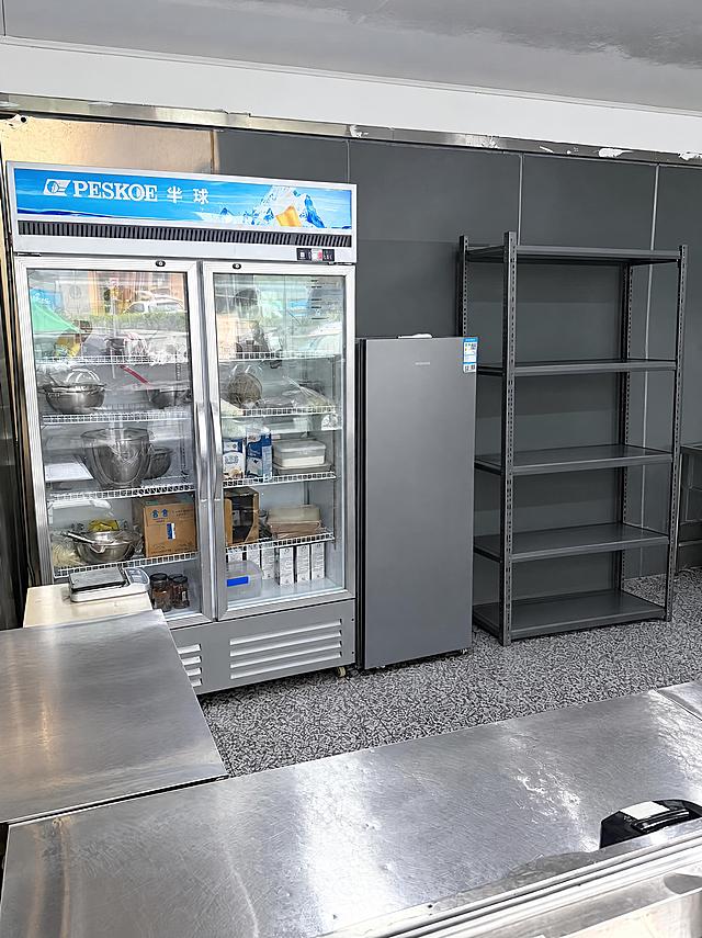 去除右侧5层金属货架上的所有物品（包括篮子、锅、塑料盒、纸箱、包装袋等所有摆放在货架上的物品），仅保留空的货架主体结构，货架的金属框架和层板完整保留。严格保持房间内其他所有主体、细节、结构、颜色、光线、透视角度完全不变，不得添加或修改任何其他元素。去除物品后的区域用周围真实的墙面、地面和货架结构自然填充，光影和材质与原图一致，过渡自然无痕。最后整体提升图片清晰度，画质自然真实，保持原照片的真实感。处理效果与同场景另一角度照片保持一致。