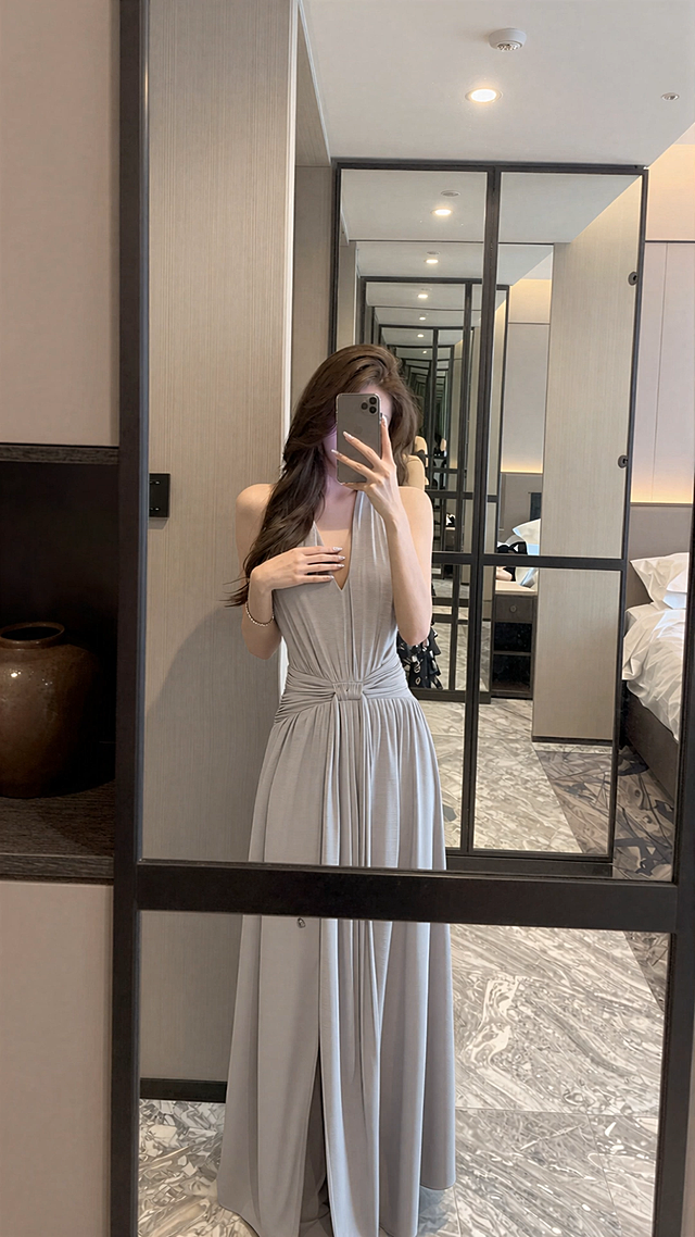 固定镜头，人物一只手举着手机对镜自拍，手机不要放下来，另一只手撩一下头发并且往前走两步，撩完头发之后自然的轻抚衣物，幅度小，模特展示穿搭，动作自然且协调，真实自然，模特展示穿搭的过程