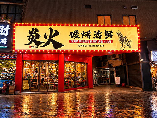 将这张烧烤店门头照片改为夜晚效果，门头灯箱整体发光，招牌文字清晰明亮，红色边框的黄色灯珠全部点亮发光，玻璃门窗透出店内暖黄色灯光，街道是夜晚氛围，地面有灯光倒影，周围环境是夜晚街景，天空深色，整体氛围热闹有烟火气，真实夜景摄影效果，光影自然逼真，高清质感