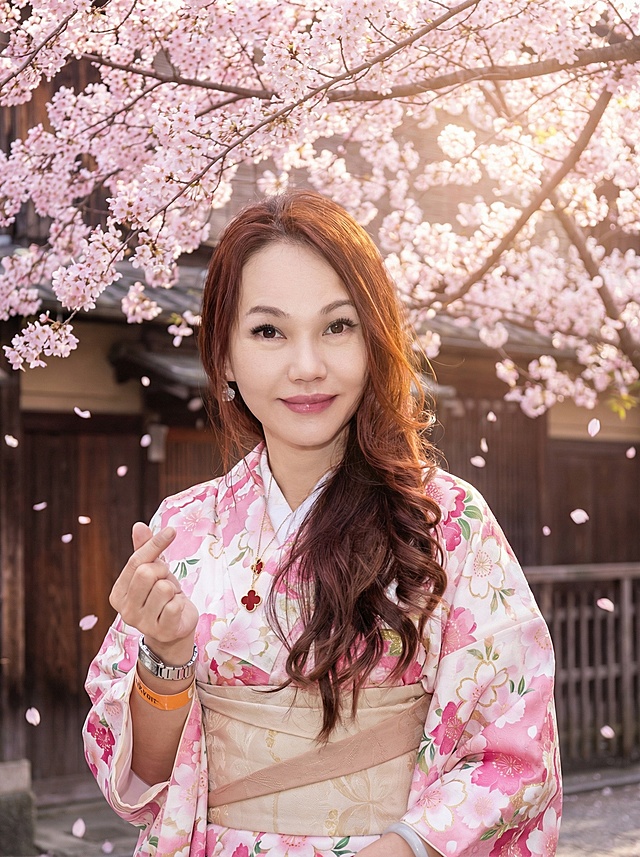 手拿着伞全身站在樱花树下