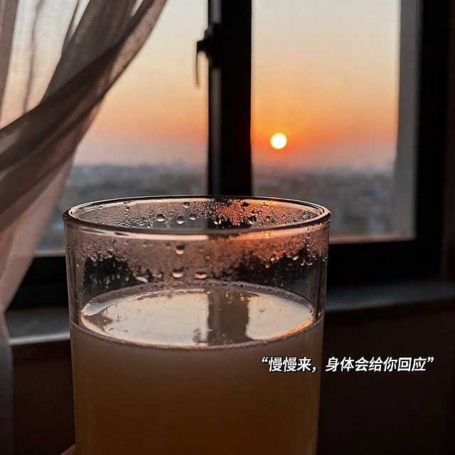 窗边黄昏时分，一杯喝了一半的益生菌冲饮，杯口带有真实水渍，窗外是渐暗天色与夕阳，窗帘被风吹起，温暖柔和的黄昏自然光，特写构图聚焦杯子，背景虚化，小字号文字“慢慢来，身体会给你回应”