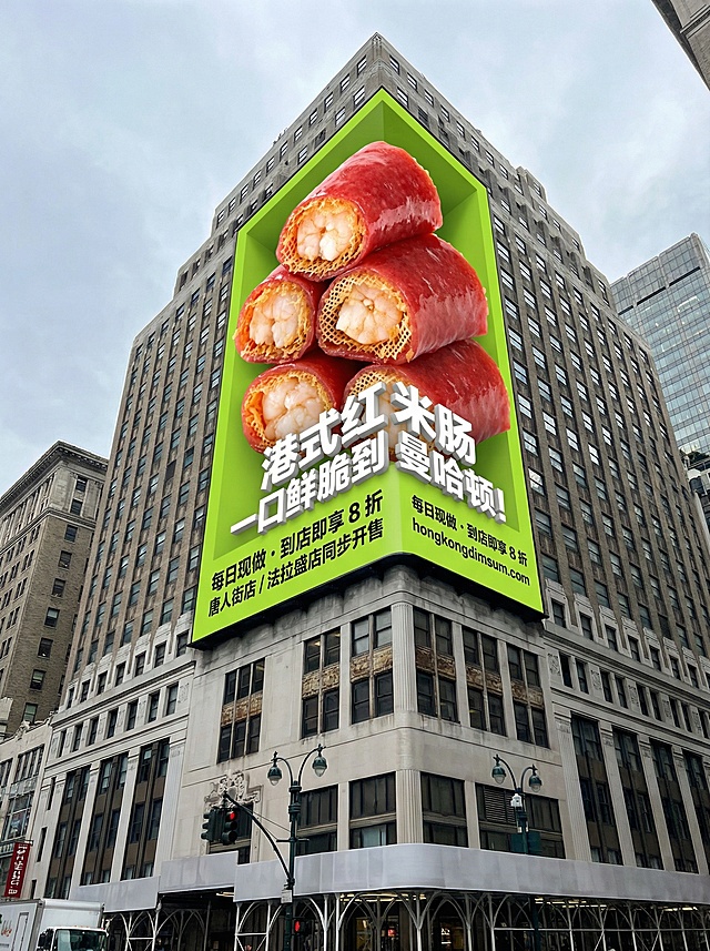 低角度仰拍纽约曼哈顿街角一栋经典石砌摩天大楼的外墙，建筑外墙上悬挂着一块巨型裸眼 3D 广告牌，背景为鲜亮的石灰绿，广告牌上堆叠着数只巨型 3D 港式红米肠，红亮通透的肠衣包裹着金黄的网状炸皮，露出饱满弹嫩的虾仁内馅，细节清晰可见。广告牌中间位置印有醒目的白色促销标语：“港式红米肠 一口鲜脆到曼哈顿！”，下方标注黑色字体的促销信息与门店指引：“每日现做・到店即享 8 折 | 唐人街店 / 法拉盛店同步开售 | hongkongdimsum.com”。整体采用超写实 3D 渲染风格，呈现出强烈的裸眼立体效果，色彩明快鲜艳，细节清晰锐利，背景是略带阴云的城市天空，自然的都市光线让广告牌在建筑外墙上显得格外醒目，营造出充满烟火气与吸引力的街头美食氛围。