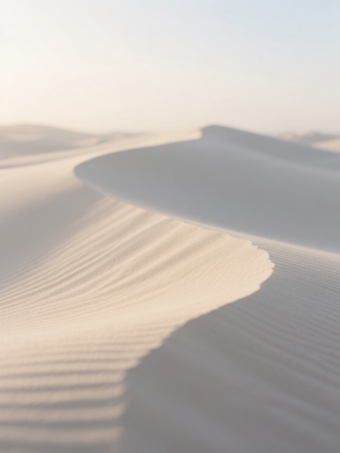 微距视角下，纯净白色渐变背景下，柔和起伏的米黄色沙丘细腻纹理清晰可见，上方柔和光线洒下形成微妙明暗过渡，宁静开阔如沙漠黎明，仅沙粒与光影纯粹对话的干净极简沙地特写背景素材预览效果