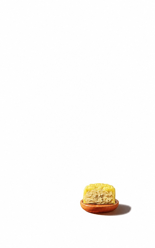 将第一张图中小木碟上的月饼替换为第二张图中的榴莲冰皮月饼（黄色冰皮、切开露出榴莲果肉内馅），保持第一张图的纯白背景、木碟位置、光影角度和整体构图风格，月饼自然放置在木碟上，质感真实自然