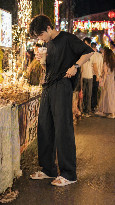 场景：城市夜市街头，夜晚暖黄色霓虹灯与路灯交织，光线柔和有层次；背景是热闹的夜市摊位与人群，自带夏日烟火气，光线清晰呈现裤子耐脏、易打理与百搭特性。模特身着黑色 oversize 短袖 + 白色拖鞋，预览效果