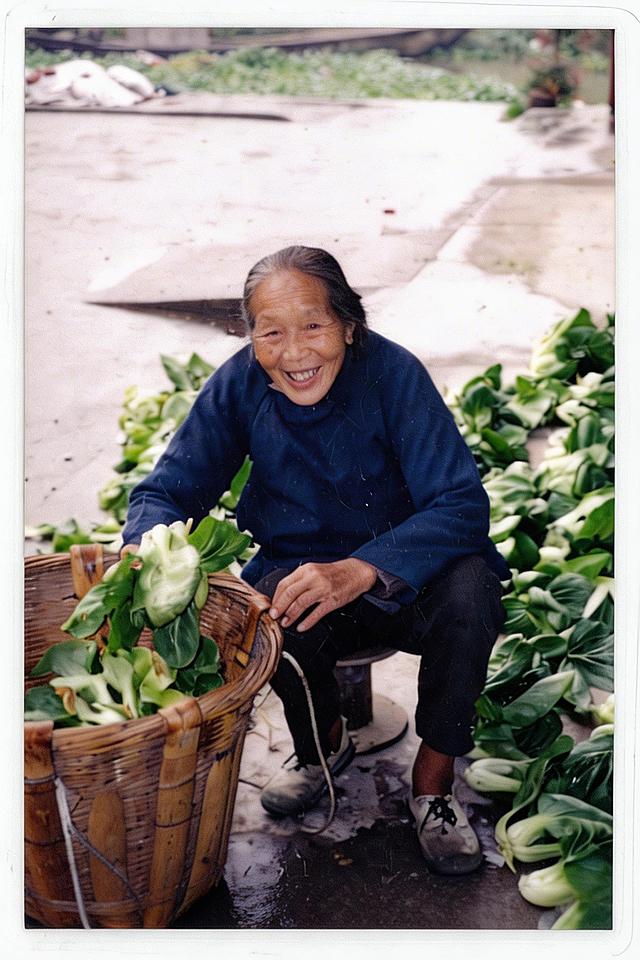 生成竖版近距离高清5寸照片，保留老人和青菜的核心内容，裁剪放大人物面部区域，提升照片清晰度和画质，保留原照片怀旧真实风格