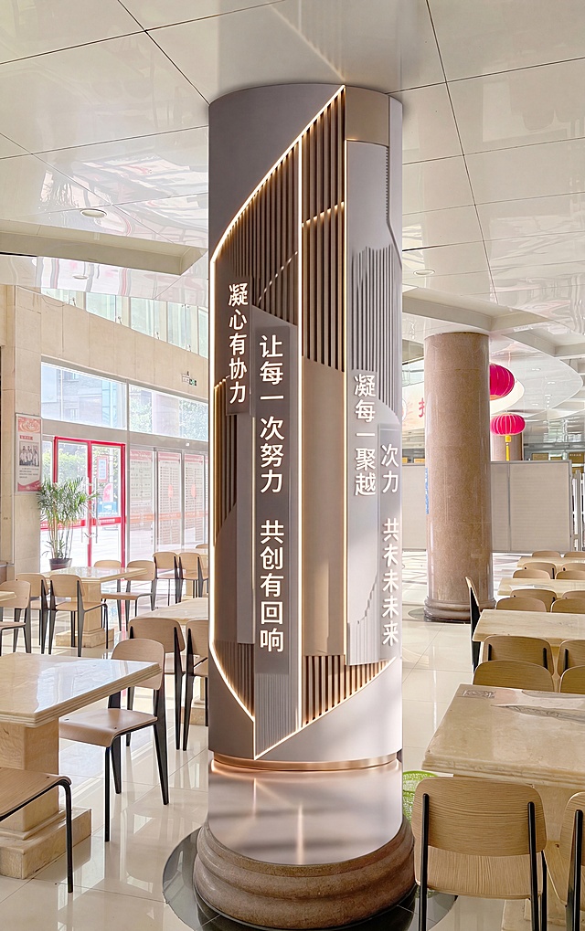 将图一中的圆形柱子改造成图二的轻奢风格文化柱子，保留原图餐厅环境和桌椅，柱子做成浅灰白色加金色金属线条，设计多层格栅加发光灯带，保留柱子圆柱形态，添加企业文化标语，保持整体空间和原图一致，只修改柱子外观风格和装饰设计