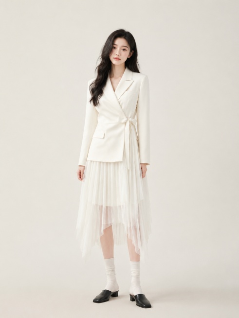 年轻东亚女模特，黑色慵懒长卷发，淡韩系淡妆，正身姿态；米白色交叉绑带收腰西装上衣，下摆拼接不规则长短百褶雪纺纱裙，西装挺括垂顺，百褶纱轻盈通透；白色堆堆中筒袜，黑色穆勒小皮鞋；纯色浅米色无缝影棚背景，预览效果