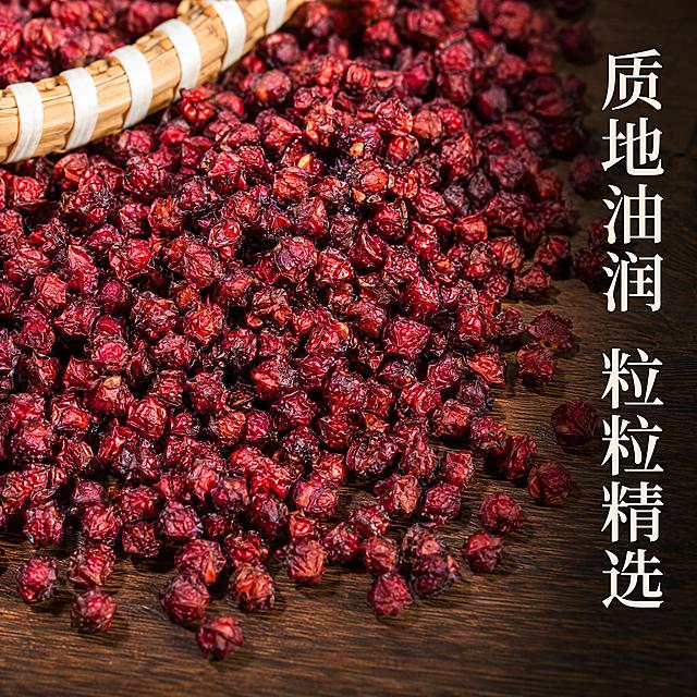 电商主图第二张，北五味子细节特写。画面以微距视角展示大量紫红色北五味子颗粒平铺铺满画面，颗粒饱满，质地油润，表面有自然光泽。背景为深棕木质纹理桌面，隐约可见竹编簸箕边缘。右侧竖排文字：'质地油润 粒粒精选'，字体为宋体风格，米白色。画面下方有少量留白。自然侧逆光照射，突出果实的立体感和油润质感，每颗果实轮廓清晰。商业美食摄影风格，超高清细节。保持五味子产品外观、颜色、质感与输入产品图绝对一致。1:1正方形构图。