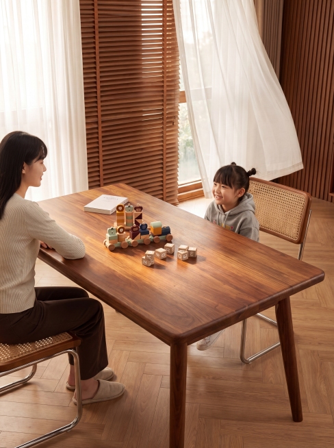 长方形实木餐桌板，北美黑胡桃木材，清晰自然木纹，圆角边缘，保持产品原有形态、纹理和颜色完全不变，严禁扭曲拉伸变形。
放置在温馨原木风客厅，暖棕木色调，搭配两侧藤编餐椅，参考图片整体客厅场景构图和氛围，预览效果