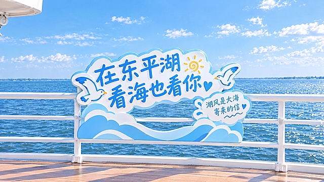 参考图中的清新治愈卡通风格，生成第一个东平湖看海主题立体字造型打卡牌：不要镂空，只有字体造型，PVC立体字，云朵波浪造型底座，主文字"在东平湖 看海也看你"，辅助小字"湖风是大海寄来的信"，装饰元素：小海鸥、小太阳、小爱心，马卡龙蓝白配色，简约大气不花哨，文旅风，适合单人打卡，尺寸适中。牌子镶嵌在游船白色栏杆上，后面是辽阔的东平湖湖面，晴朗蓝天，真实自然的游船甲板场景，透视准确，光影柔和，高清2K