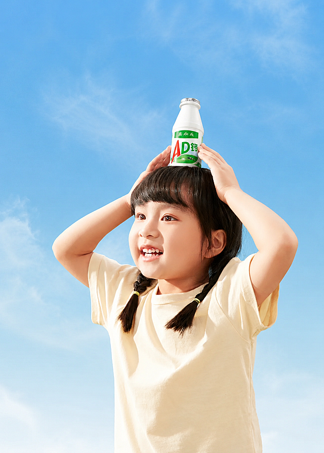 参考原图片风格，小女孩的动作和构图保持不变，去掉画面所有文字，将头顶的番茄汁饮料替换成AD钙奶，背景为清新蓝天，保留整体干净明亮的摄影风格
