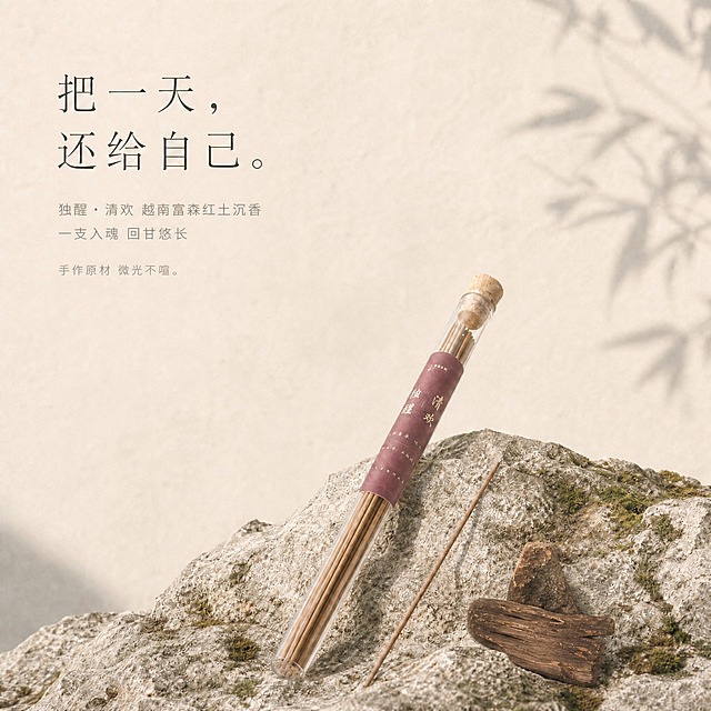 将图片右下角的干柠檬片替换成几块越南富森红土沉香原材料（沉香木块/沉香片），沉香木块呈深棕褐色，有天然木纹和油脂纹理，大小形态自然，放在石头表面，与周围环境光影一致。其余画面保持不变：玻璃管线香产品、单独一支线香、毛石青苔、米杏色背景墙、竹影、左上角文字全部保留原样。整体侘寂极简风格，柔和自然光，高级质感。