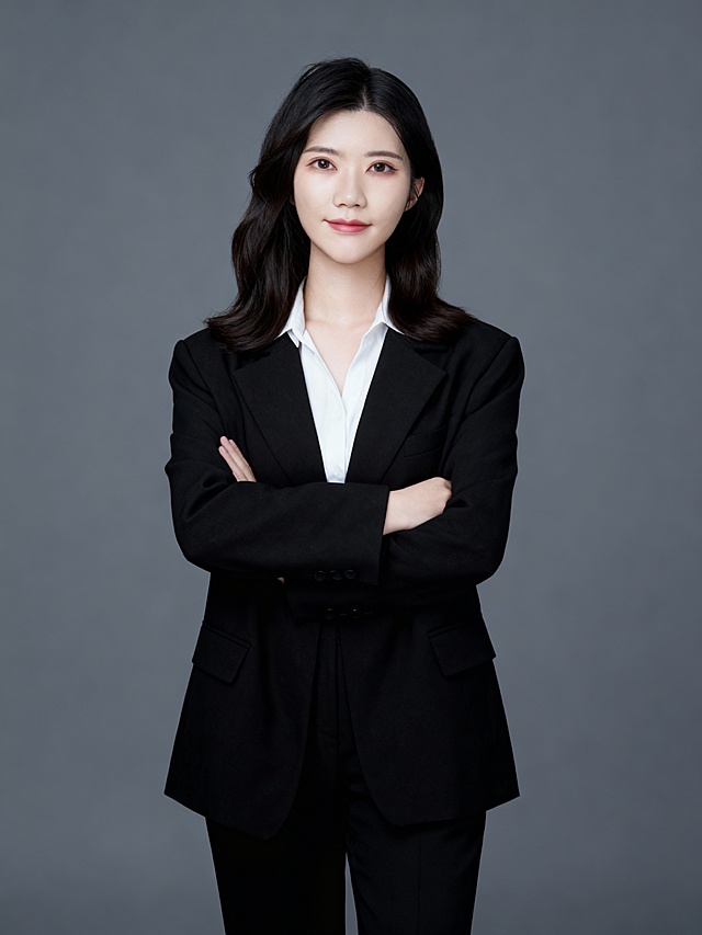 保留人物脸型､年龄特征生成标准职场形象照,50mm焦段,F/4光圈(F/2.8-F/4区间),相机与人物距离3米,横向16:9比例(左右预留环境空间),人物占画面60%,入镜头部至膝盖上方5cm,平视视角,人物居中构图,头肩比例协调,主体锐利,双侧打柔和光,美颜磨皮韩式精致浓妆,均匀肤色提亮肤色,身穿黑色亚面oversize精纺面料西装,黑色亚面精纺面料西裤;白色衬衫内搭,双臂自然抱胸,自信从容;站立姿势,温婉感,中长发披肩,弧度自然,发尾微卷内敛沉稳,眼神直视镜头,目光坚定且澄澈,表情自然.嘴角微微上扬,气质自信从容;均匀肤色,专业人像摄影写真,头部完整,结构准确;光比1:1.5,4800K暖调中性光,修饰脸型,肤质哑光细腻,轻透裸肌感,真实毛孔纹理,32K画质,去除人物之外的所有元素,零噪点降噪,简约冷调中深灰度纯色背景。