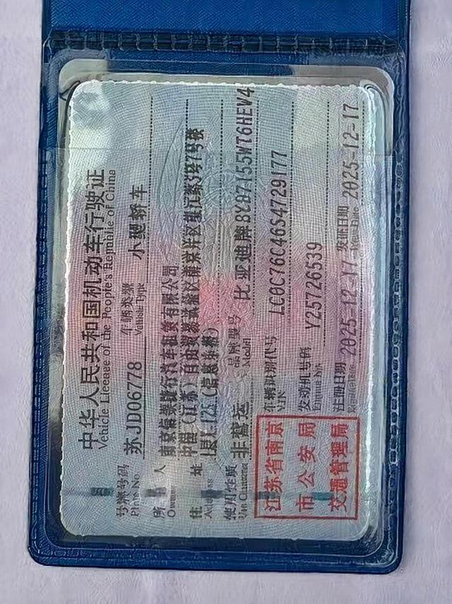 将图片中机动车行驶证上的号牌号码修改为"苏JD06778"，严格匹配旁边"车辆类型"等文字的字体（仿宋/宋体印刷体）、字号大小、字重、黑色墨色浓度和印刷质感，保持与周围文字完全一致的视觉风格，带有轻微的印刷网点和纸张纹理，位置与原号牌号码对齐，其余所有文字、印章、底纹、塑封反光效果均保持不变，修改自然无痕，无法看出修改痕迹