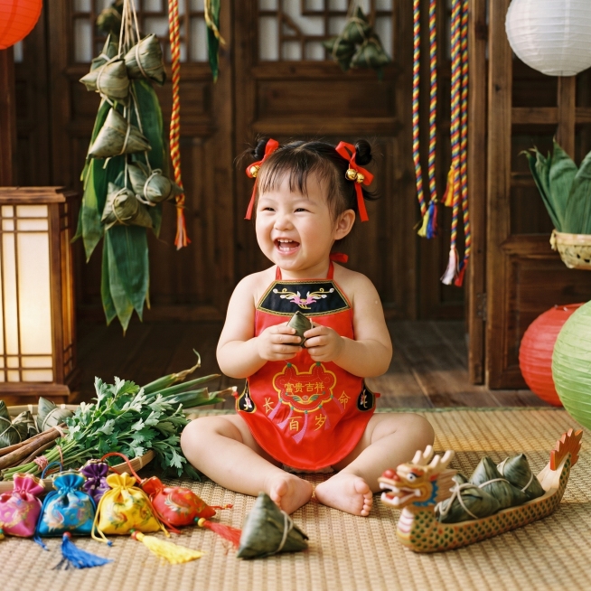 端午节氛围，照片写真，一个2岁左右白白胖胖的哪吒宝宝，留着哪吒丸子头，戴着哪吒丸子头饰，穿着参考图中的红色传统刺绣肚兜，肚兜上有富贵吉祥长命百岁字样，画面比例1:1预览效果